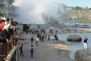 I lacrimogeni e i manifestanti che corrono verso la spiaggia 